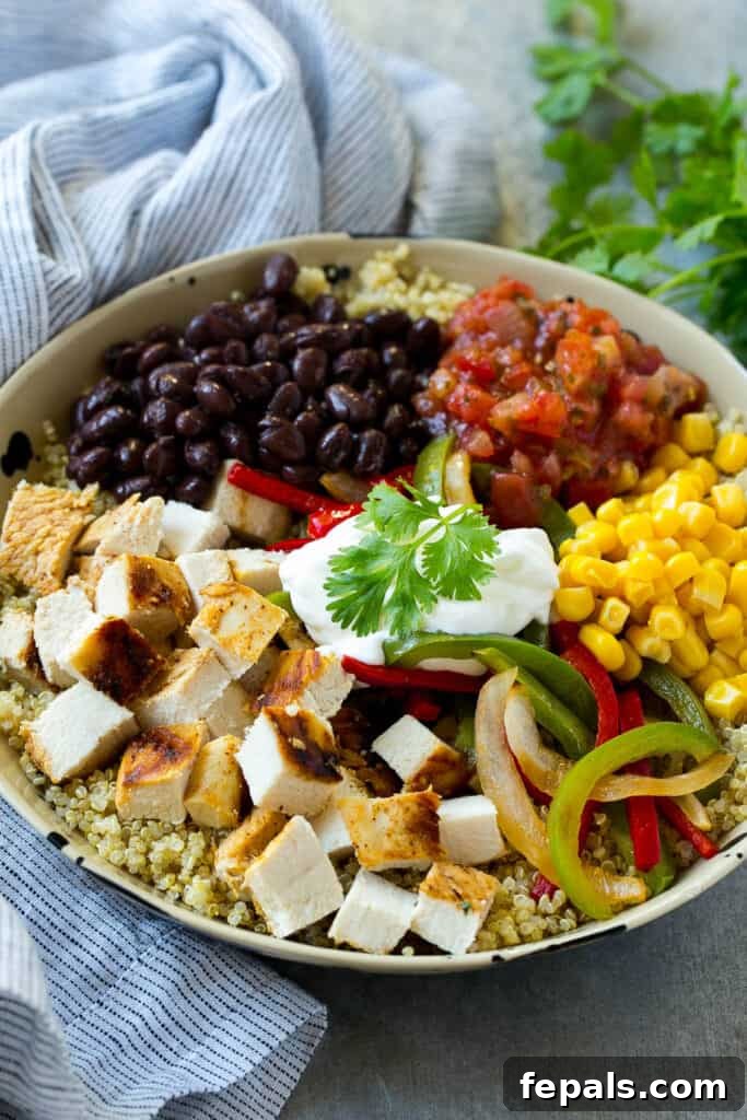 Top-down view of a generously filled quinoa bowl with chicken, black beans, corn, and salsa