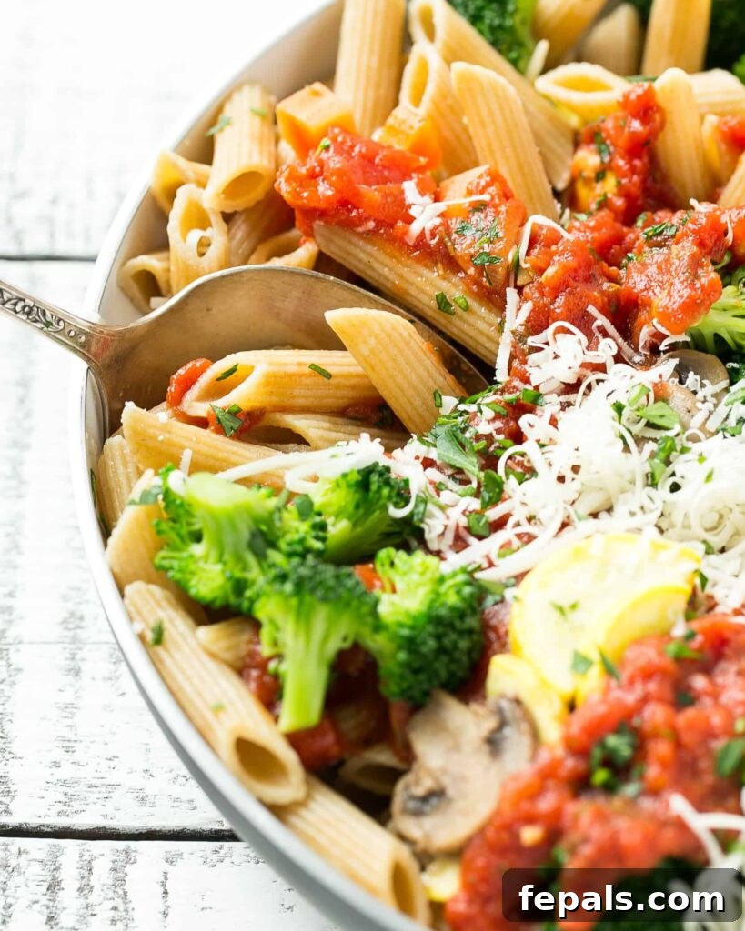 side shot of penne pasta with veggies and marinara sauce in a bowl