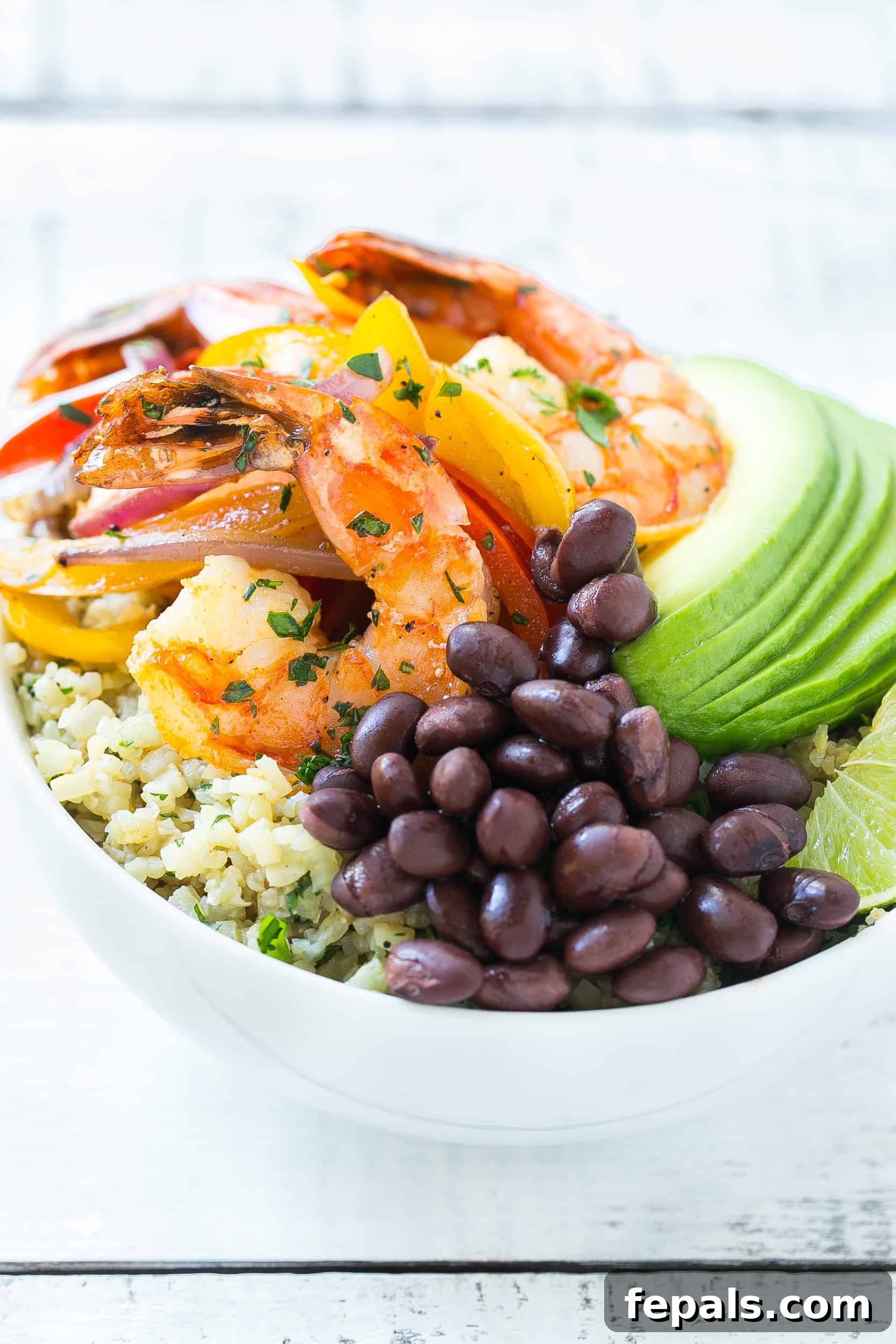 Close-up shot of perfectly cooked shrimp and black beans, ready for a fajita bowl.