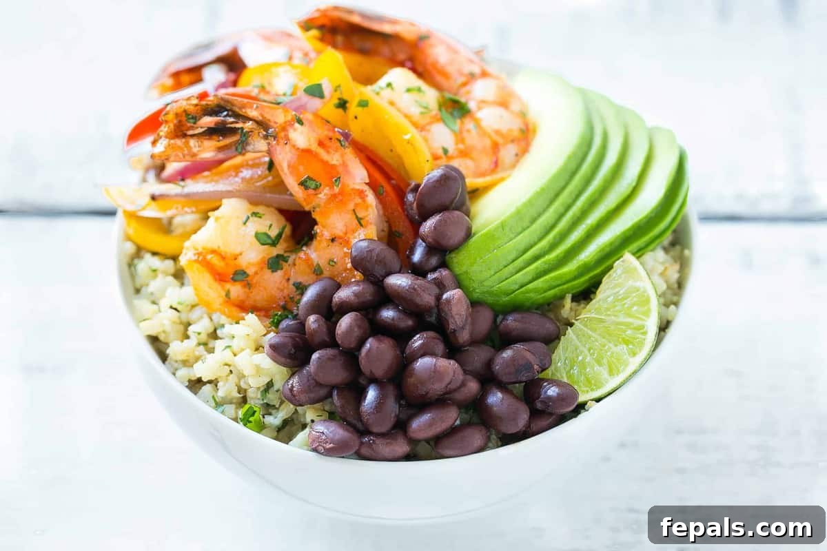 A close-up view of a fresh Shrimp Fajita Bowl, garnished with avocado slices and fresh cilantro.