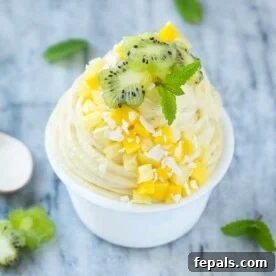 banana ice cream swirls in a small bowl topped with chopped fruits and shaved coconut.