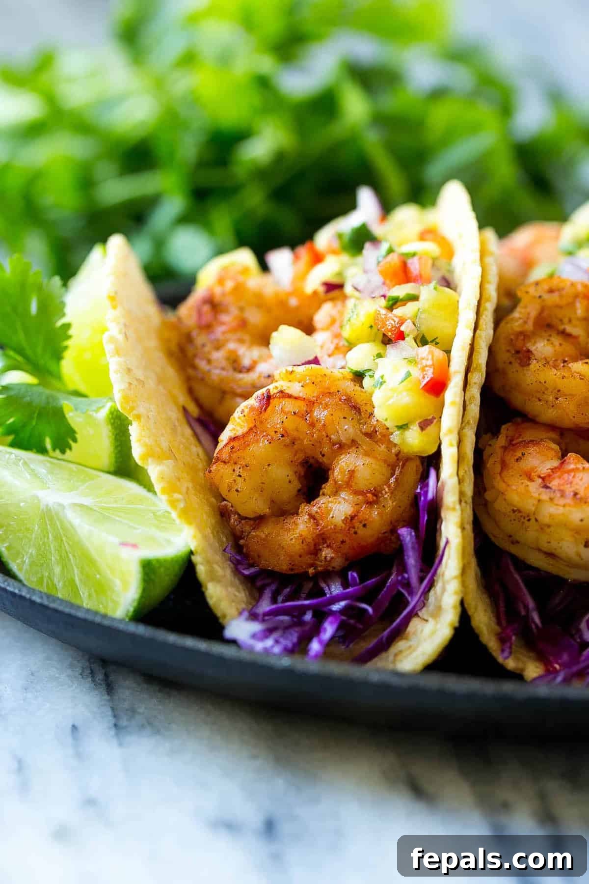 close view of shrimp taco on corn tortilla with lime and pineapple salsa