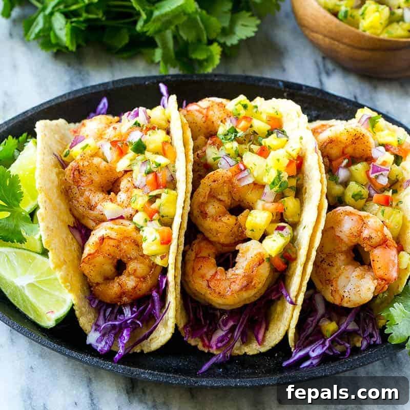 three shrimp tacos on plate with pineapple salsa