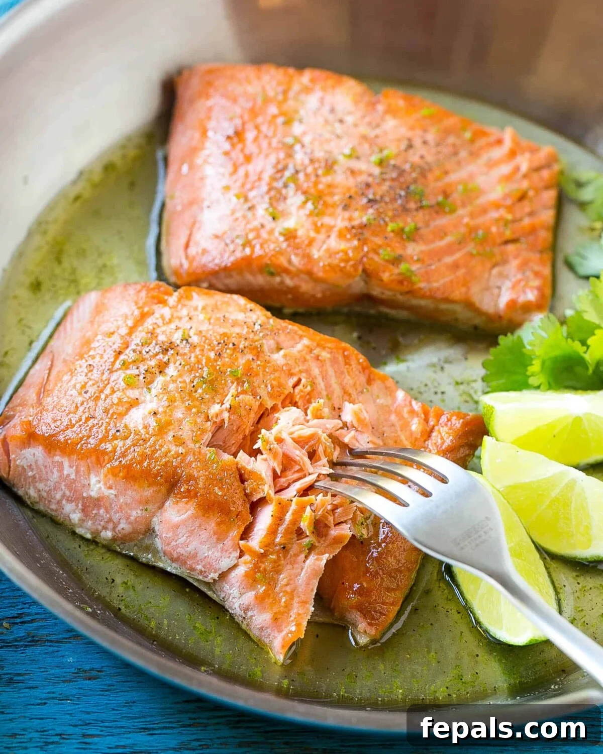 Sweet & Zesty Honey-Lime Salmon 2 Fork flaking a perfectly pan-seared honey-lime glazed salmon fillet in a skillet, with fresh lime wedges on the side, showcasing its tender texture.