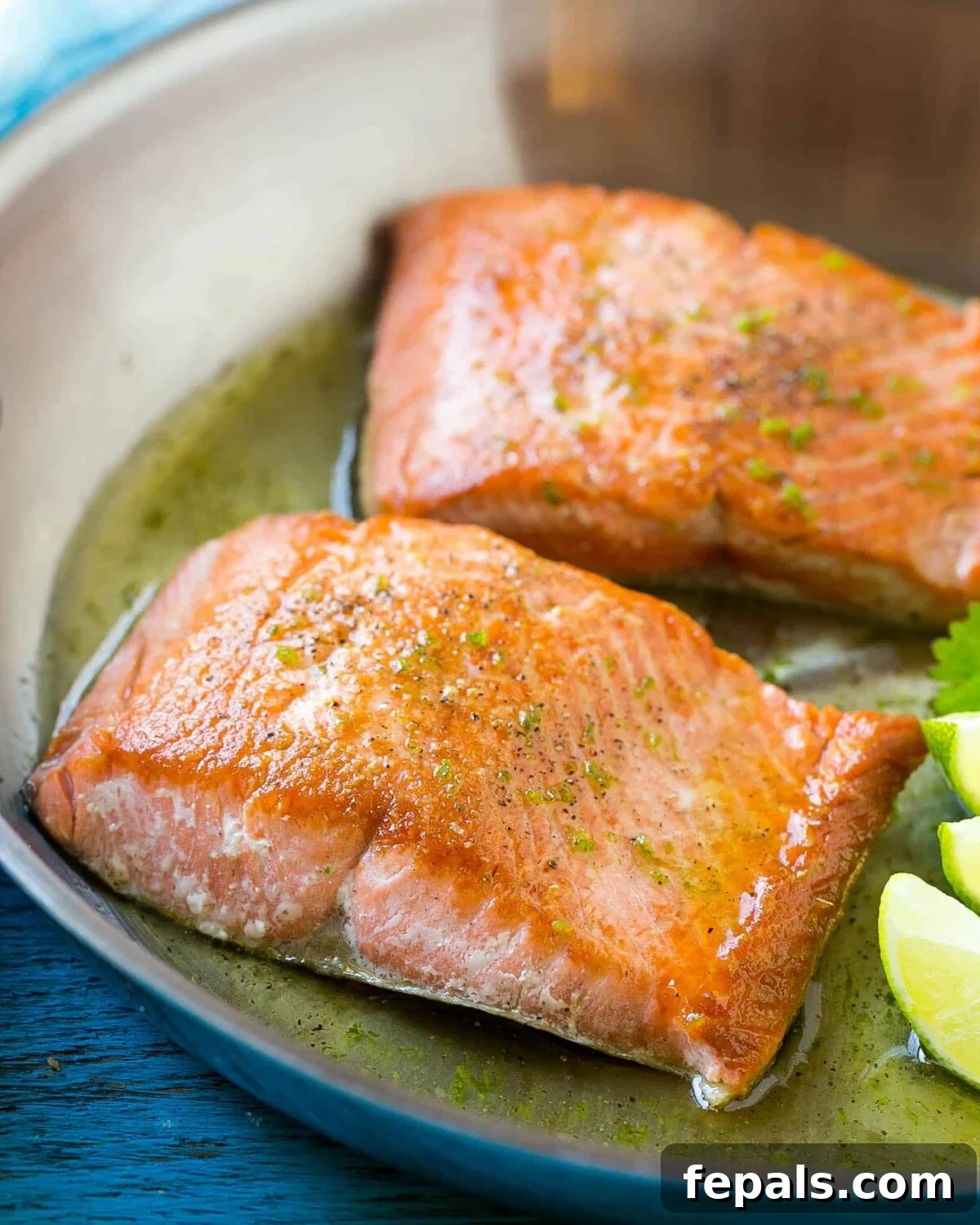 Sweet & Zesty Honey-Lime Salmon 3 Two perfectly cooked salmon fillets shimmering with lime sauce in a stainless steel skillet, ready to be served.