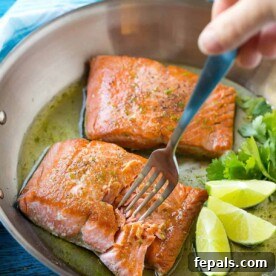 2 cooked salmon filets on a skillet with lime wedges.