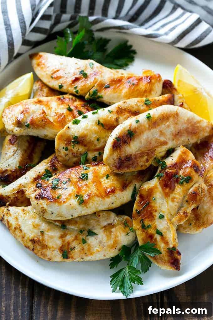 Zesty Lemon-Garlic Chicken Strips 2 Lemon garlic marinated chicken tenders arranged beautifully on a white plate, garnished with fresh chopped parsley, ready to be served.