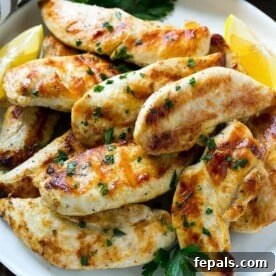lemon garlic marinated chicken tenders on a white plate topped with fresh chopped parsley