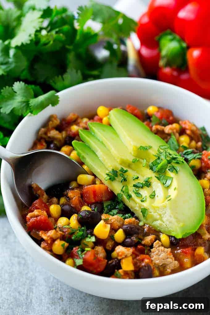 Effortless Slow Cooker Southwest Turkey Chili 4 spoon scooping up delicious slow cooker turkey chili from a white bowl, showing the rich texture and ingredients