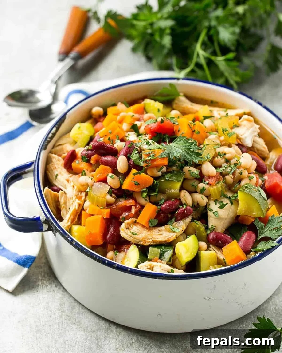A large white pot filled with bubbling Italian chicken and bean soup, ready to be served.