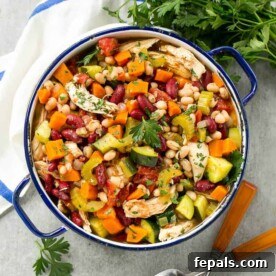 A blue and white pot filled with chicken, bean, and veggies soup.