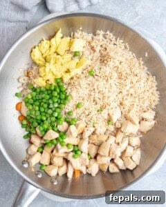 Rice, chicken, veggies, and eggs, added to a pan.