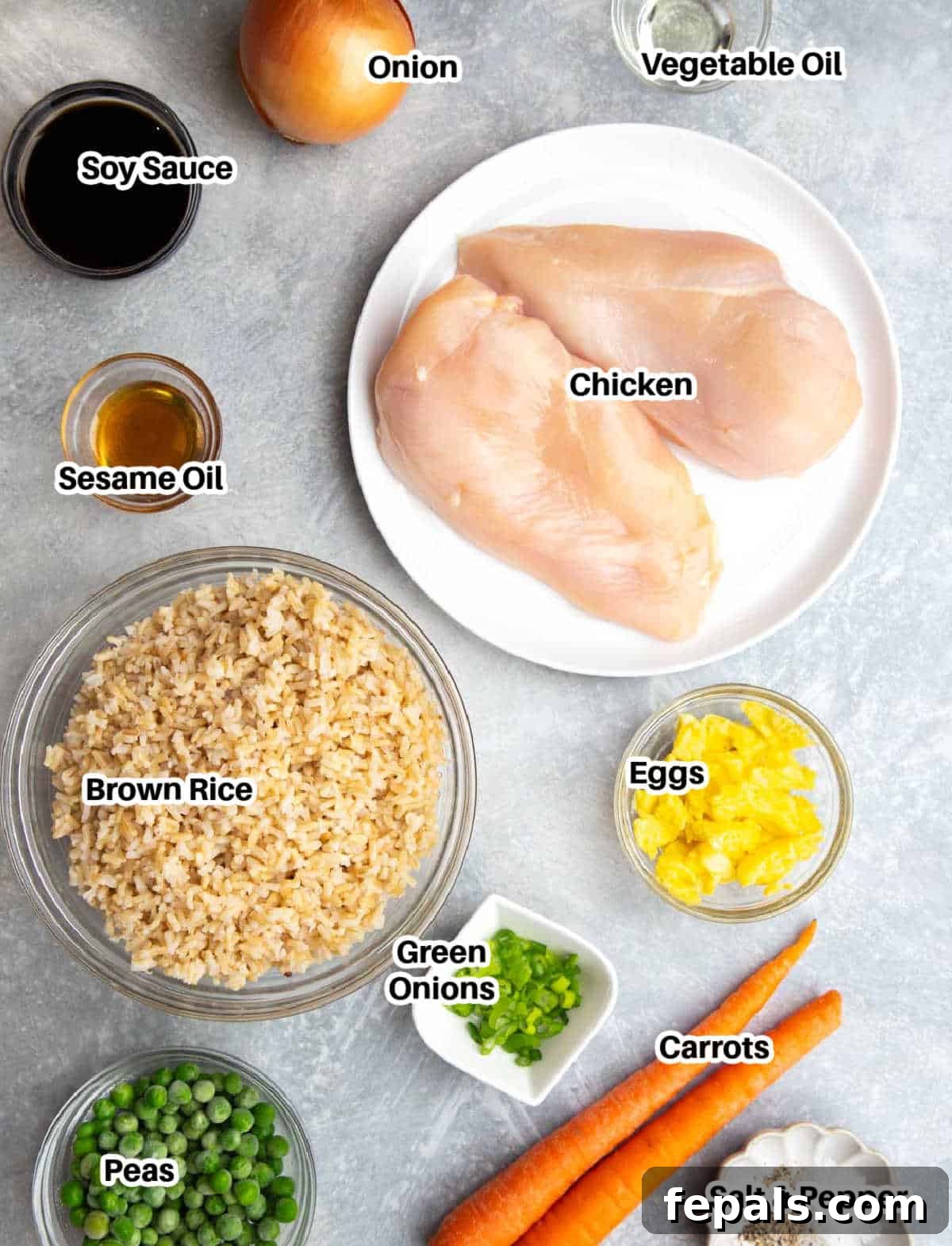 Classic Homemade Chicken Fried Rice 3 A vibrant display of fresh ingredients laid out to make chicken fried rice, including chicken breast, rice, eggs, onions, carrots, and peas.