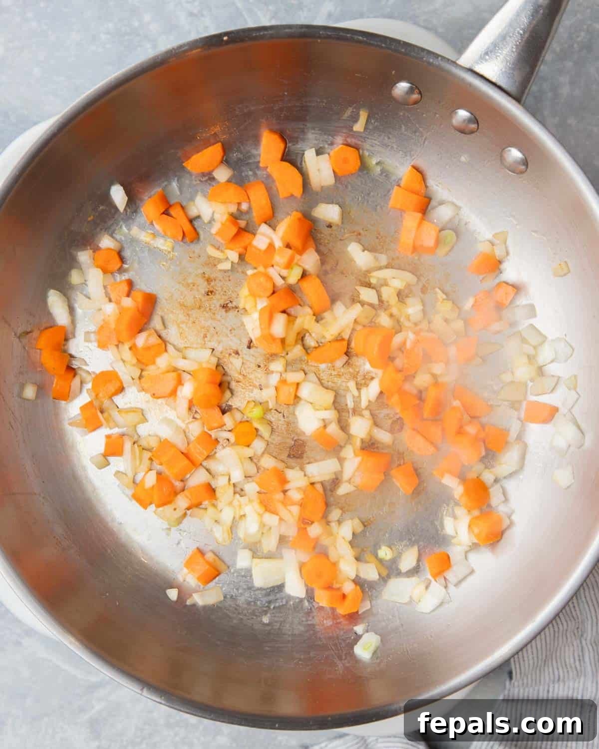 Classic Homemade Chicken Fried Rice 5 Finely chopped onions and carrots actively sautéing in a pan, softening and releasing their aromas.