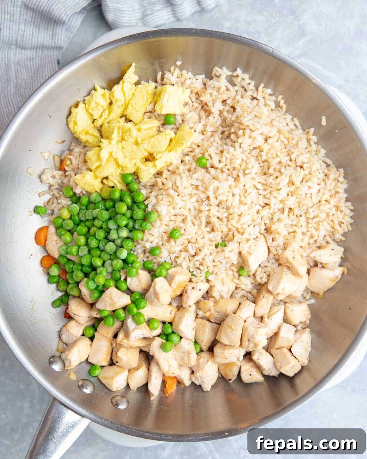 Classic Homemade Chicken Fried Rice 6 Cooked rice, chicken, scrambled eggs, and peas expertly combined in a pan, ready for seasoning.