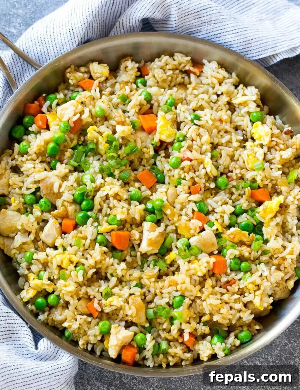 Classic Homemade Chicken Fried Rice 10 A round skillet brimming with savory chicken fried rice, colorful vegetables, and scrambled egg pieces.