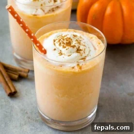 Pumpkin Spice Protein Power Smoothie 6 an orange looking pumpkin pie protein shake in a cup topped with whipped cream and a dash of cinnamon.