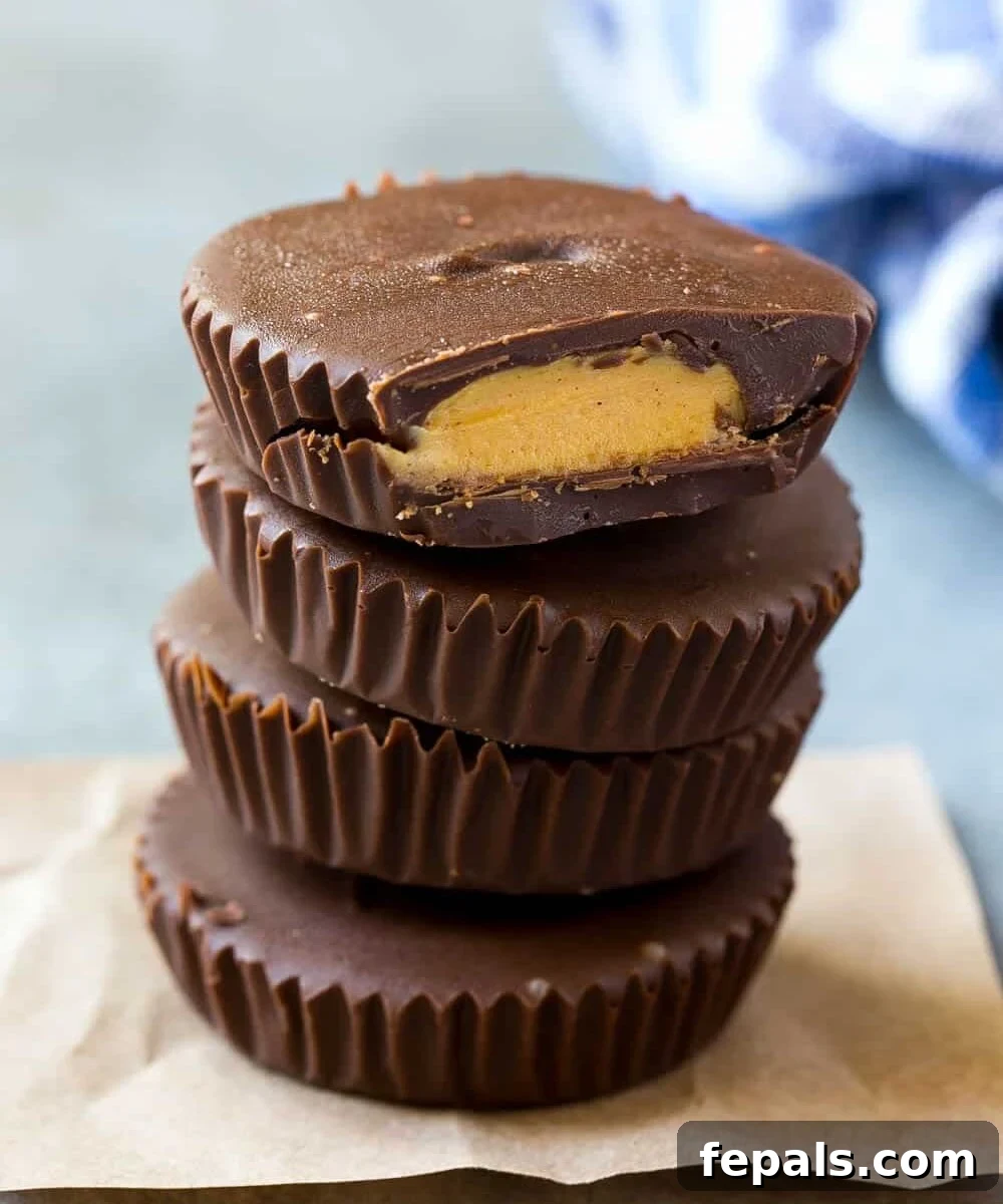Stacked Protein Peanut Butter Cups on parchment paper, showcasing their rich chocolate and peanut butter layers.