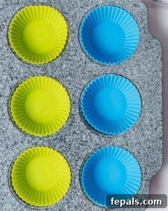 Light blue and light green silicone cup liners placed neatly in a muffin pan, ready for the first layer of chocolate.