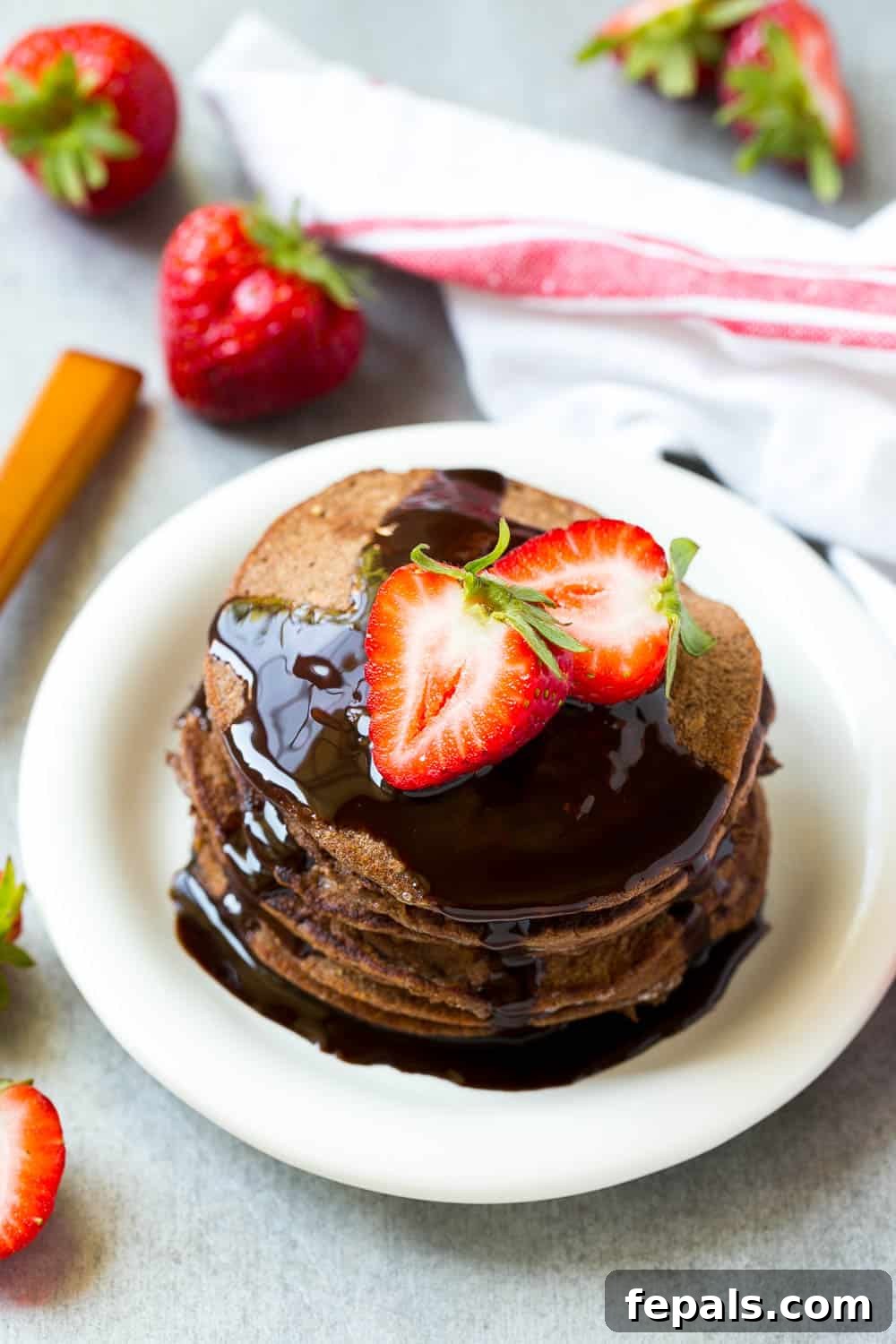 Decadent Chocolate Protein Pancakes 2 A stack of fluffy chocolate protein pancakes drizzled with syrup and topped with fresh berries.