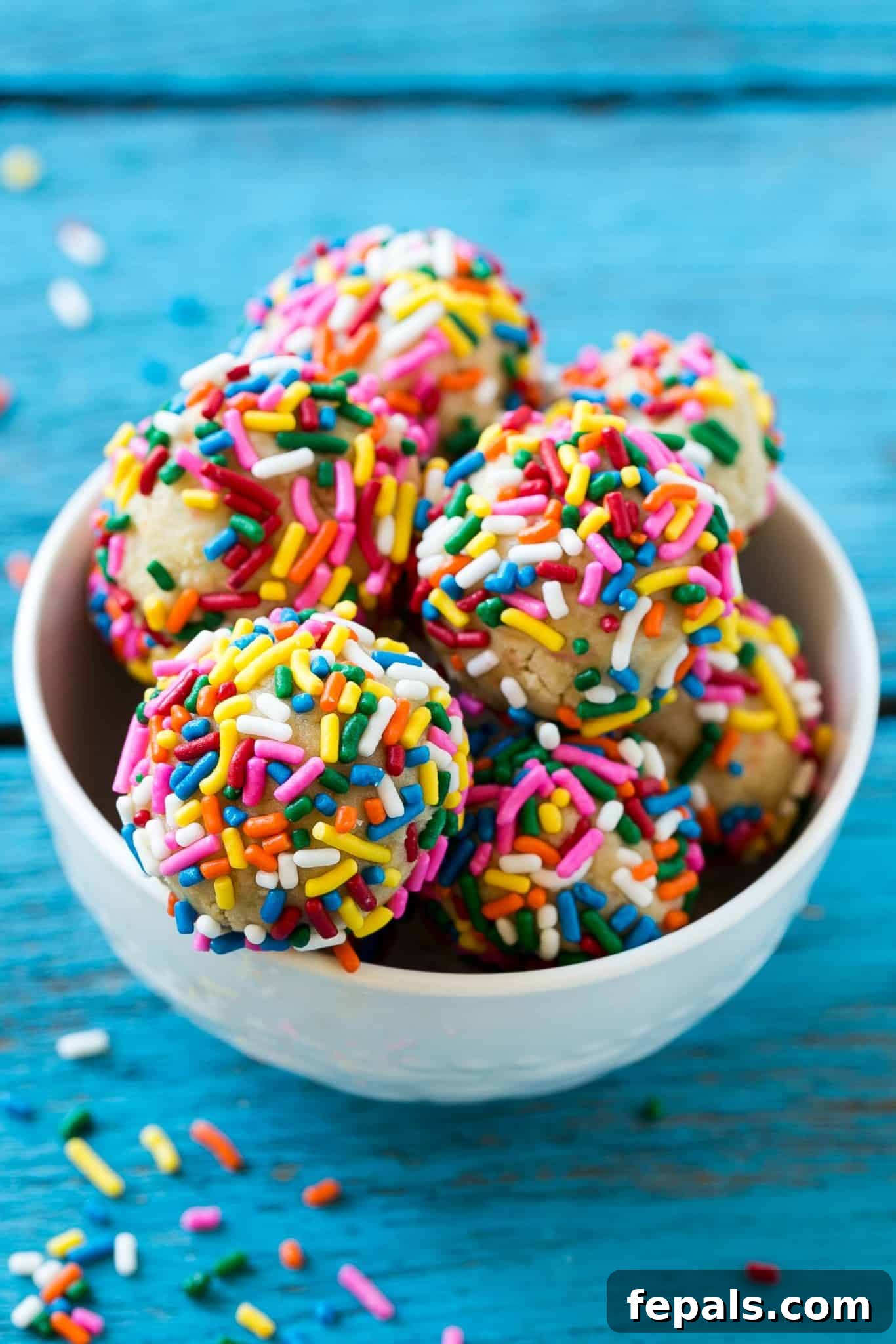 Delicious birthday cake protein bites in a white bowl, sprinkled with colorful confetti.