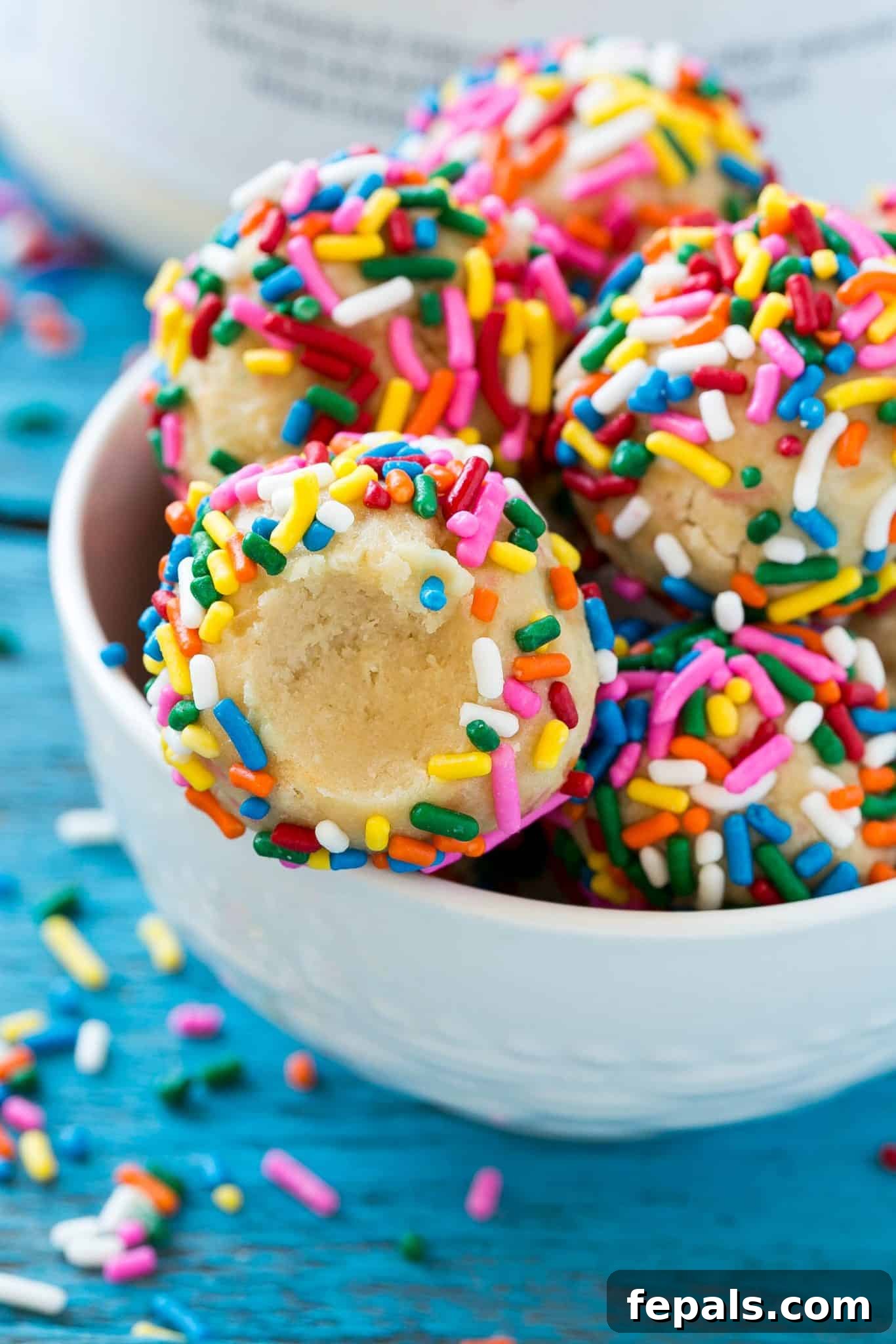 Close-up of no-bake protein bites with colorful sprinkles in a white bowl.