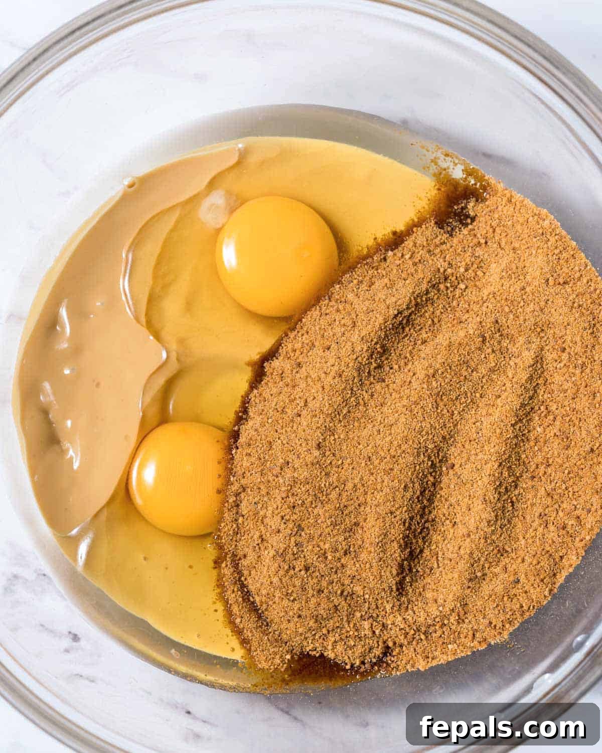 Power-Packed Protein Chocolate Cookies 5 Coconut sugar added over peanut butter and 2 eggs in a clear bowl, ready for mixing.