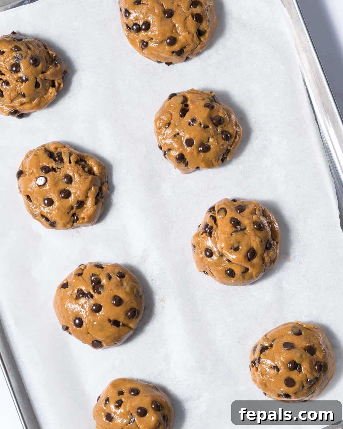 Power-Packed Protein Chocolate Cookies 10 Raw cookie dough balls arranged on a baking sheet lined with parchment paper, ready for baking.