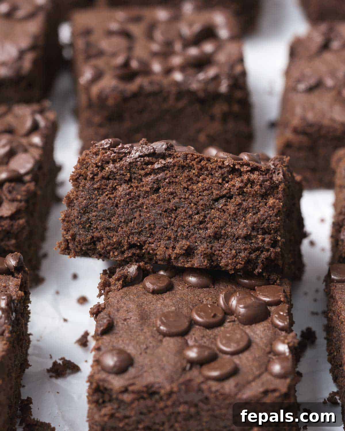 Two squares of rich, dark protein brownies stacked on top of each other, highlighting their fudgy interior.