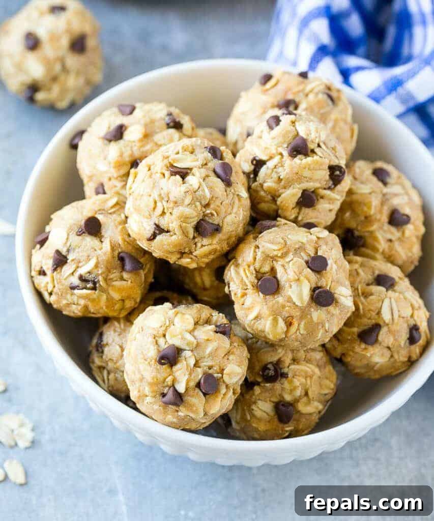 Top view of a white bowl filled with delicious no-bake protein energy bites, made with oats, peanut butter, and chocolate chips, next to a white and blue kitchen towel.