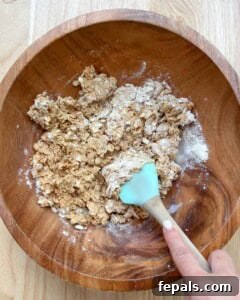using a spatula mixing the oats, peanut butter, honey, and protein powder in a bowl.