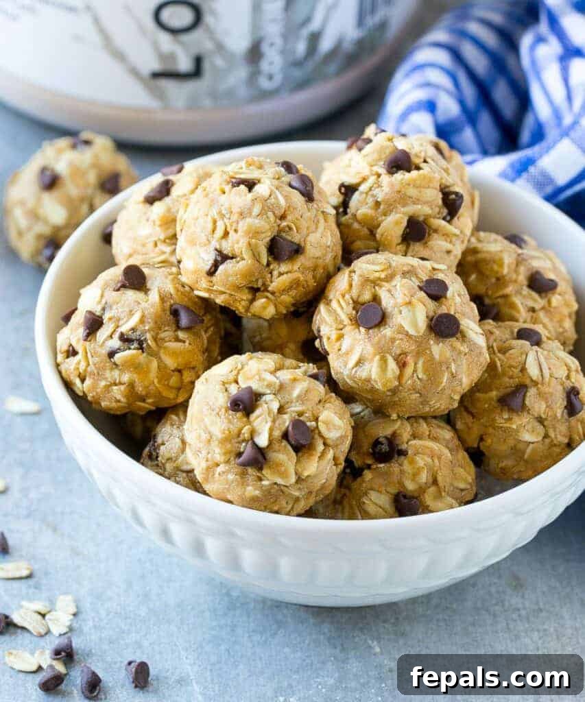 A side shot of a small, round white bowl filled with numerous freshly made protein energy bites, ready for chilling.