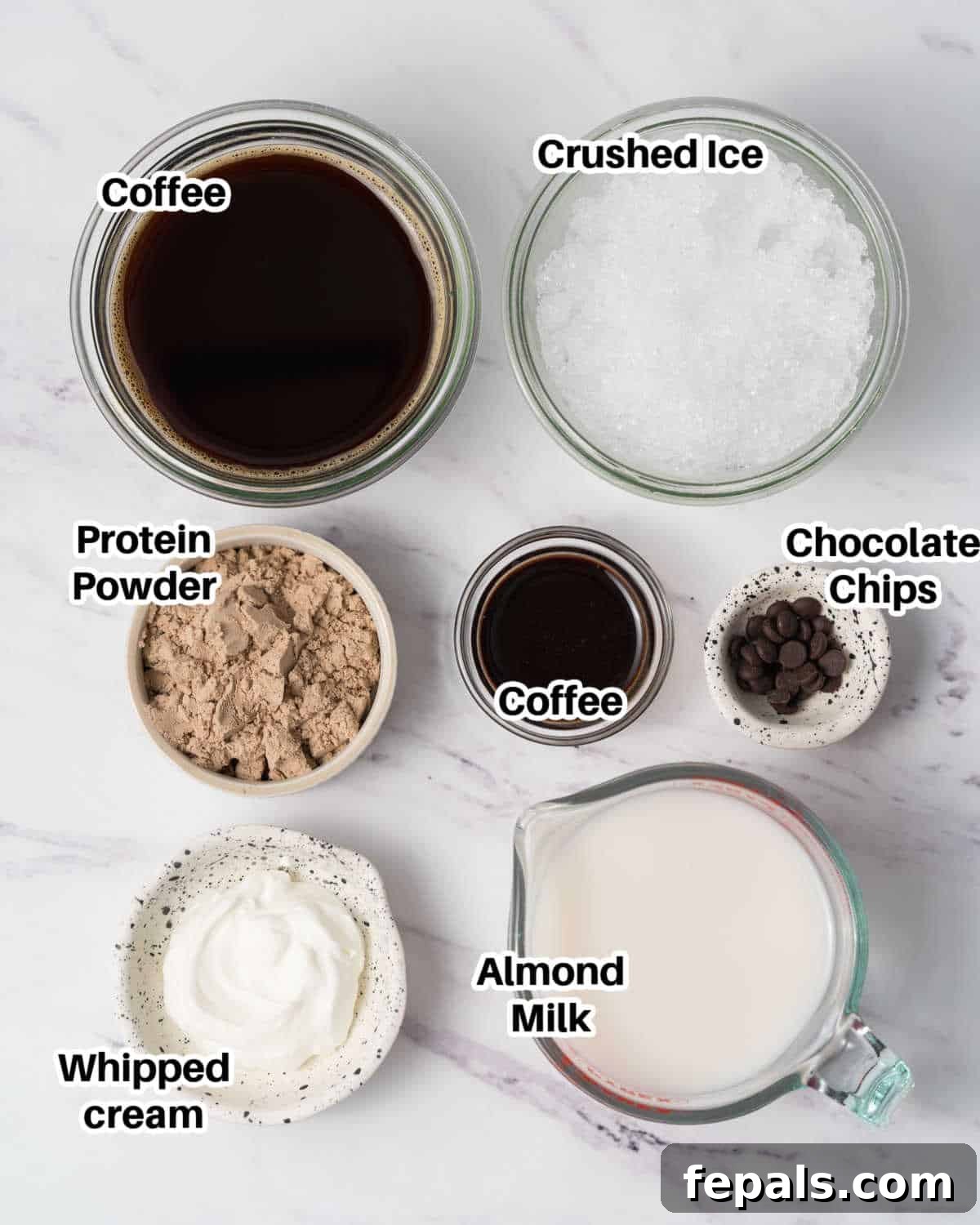 A flat lay of all the essential ingredients laid out to make a delicious and nutritious mocha protein shake, including coffee, milk, protein powder, and chocolate syrup.