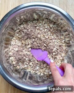 hand holding purple spatula mixing the dry ingredients.