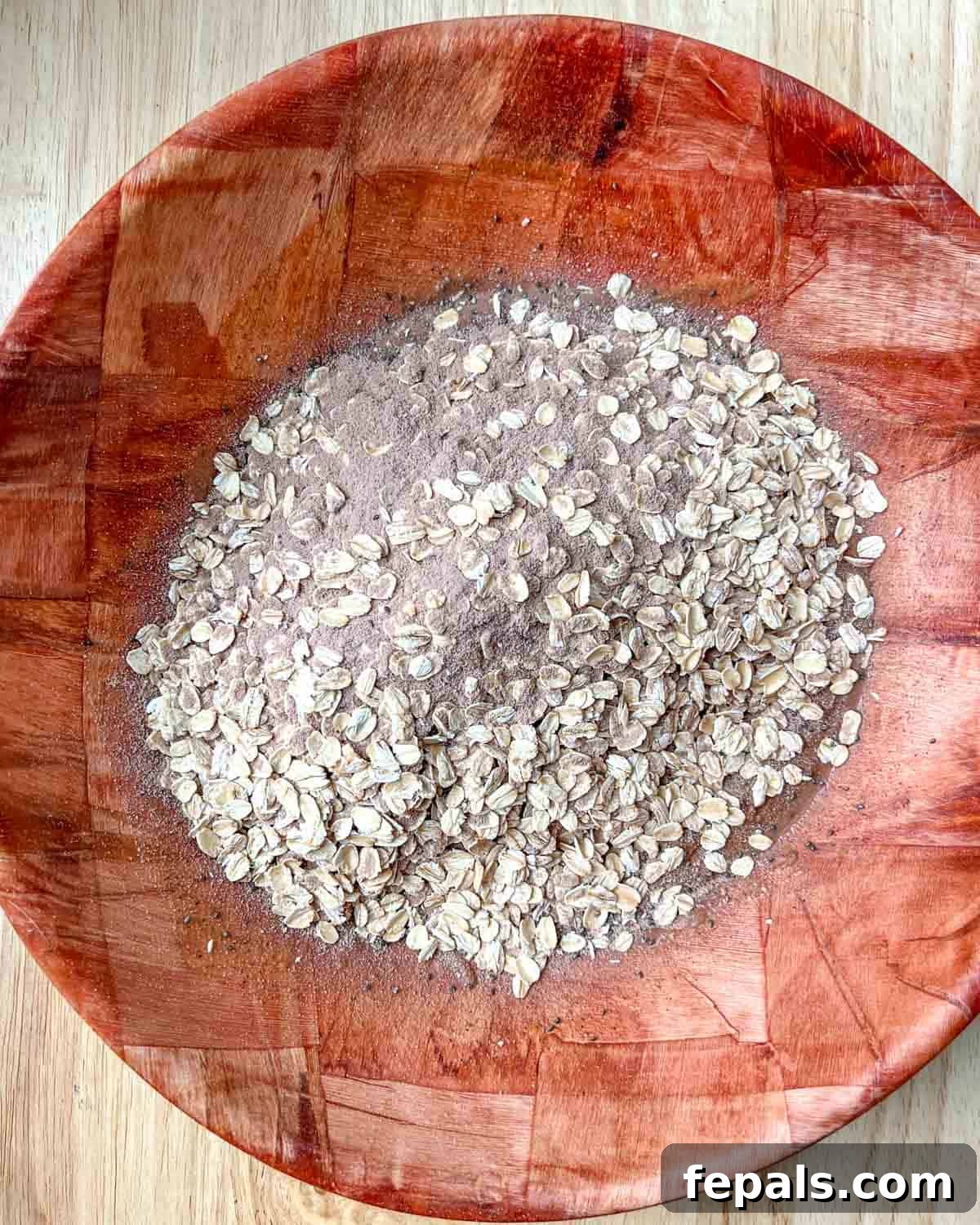 The combined dry oat and protein mixture being poured over the creamy nut butter, honey, and coconut oil mixture.