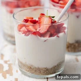 A clear cup with no bake cheesecake topped with fresh chopped strawberries.