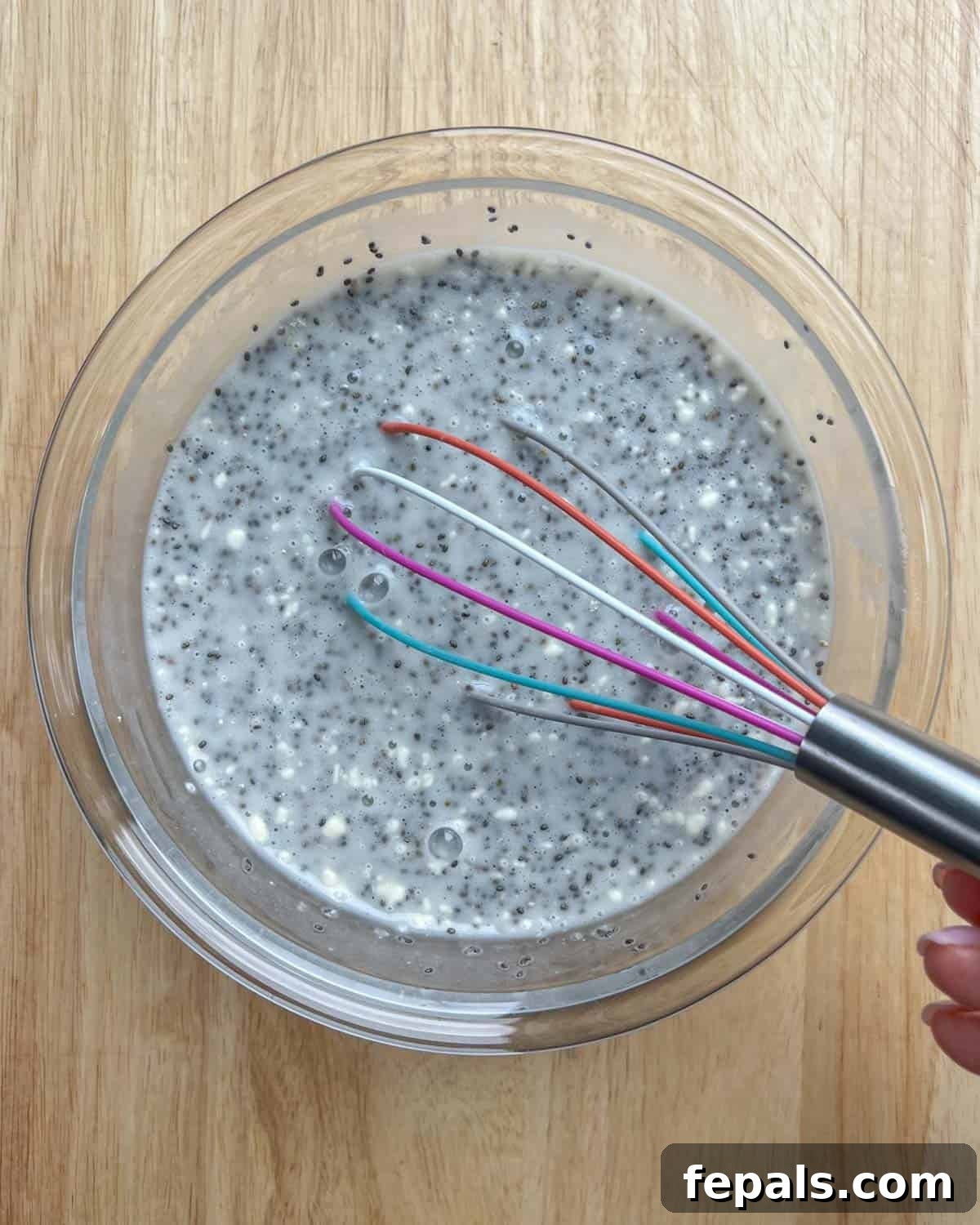 Creamy Coconut Chia Seed Pudding 3 Chia seeds, coconut milk, maple syrup, and protein powder being whisked together in a bowl.