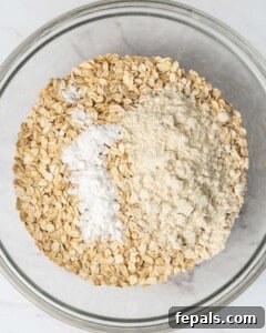 Oats, baking powder, and protein powder are added to a round bowl.
