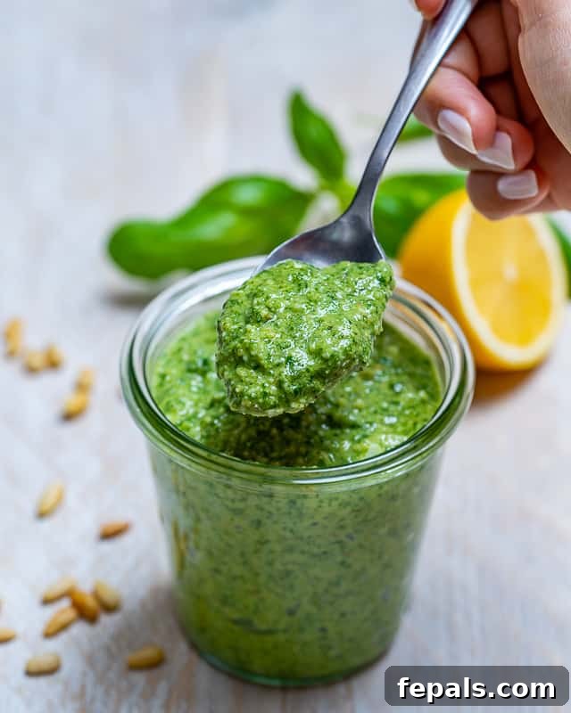 Garden Fresh Pesto Bliss 2 homemade pesto recipe with basil in a jar with a spoonful of pesto and a slice of half lemon behind the jar