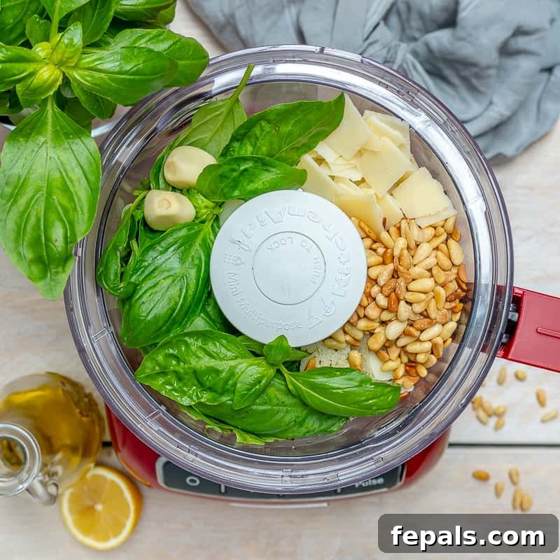 Garden Fresh Pesto Bliss 4 top view of food processor with fresh basil, pine nuts, garlic, and shaved parmesan cheese in it