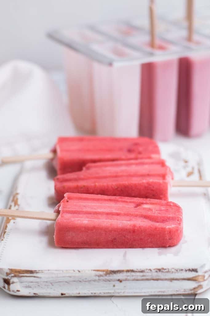 Strawberry Bliss Vegan Pops 4 4 Strawberry Popsicles on a flat surface cutting board, ready to be served