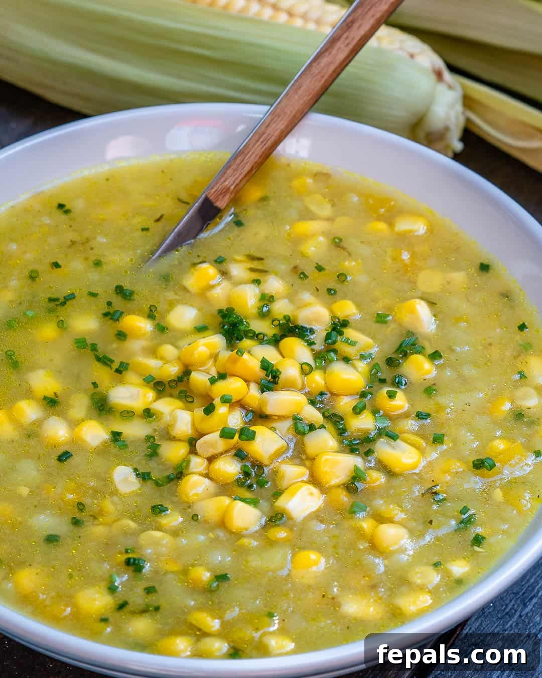 Wholesome Sweet Corn Chowder 4 Corn chowder soup in a pot with a wooden spoon in the pot.