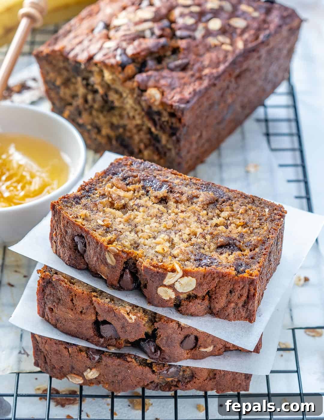 Stacked slices of healthy chocolate chip banana bread on a metal wire rack, showcasing its moist texture.