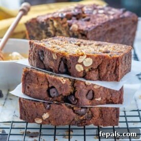 Three slices of healthy chocolate chip banana bread stacked over each other on a wire rack, showcasing the oatmeal and chocolate chips.