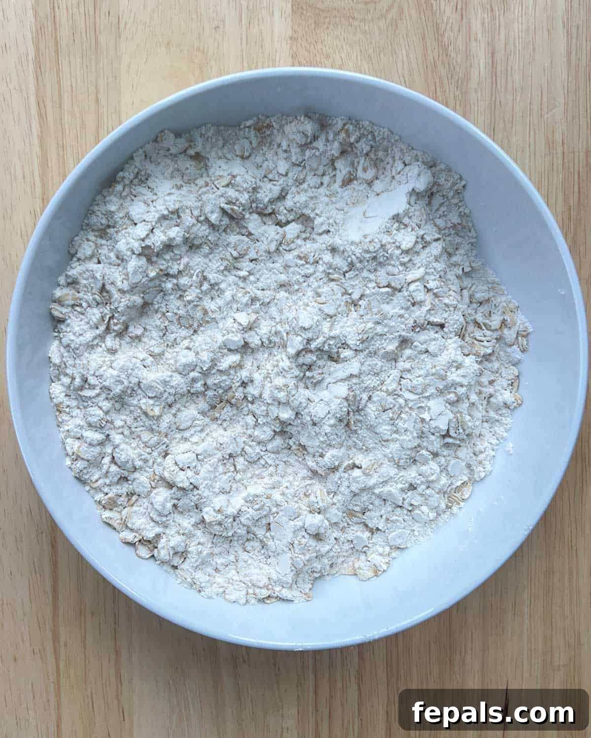 Dry flour ingredients mixed thoroughly in a round white bowl, prepared for banana bread batter.
