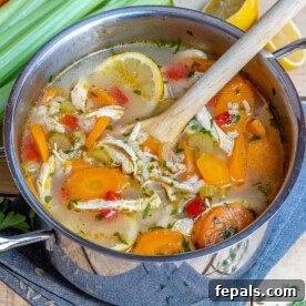 A beautifully plated bowl of chicken and rice soup, with a wooden spoon resting in the pot, inviting you to taste.