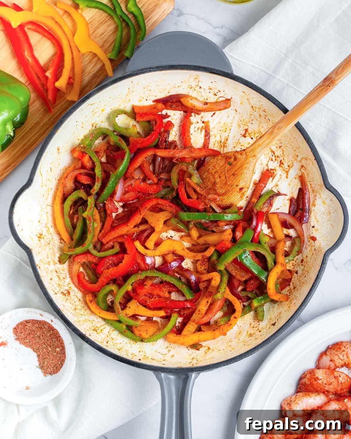 The vibrant bell peppers and onions, now tender-crisp and perfectly cooked, are seasoned and ready to be set aside before the shrimp is cooked.