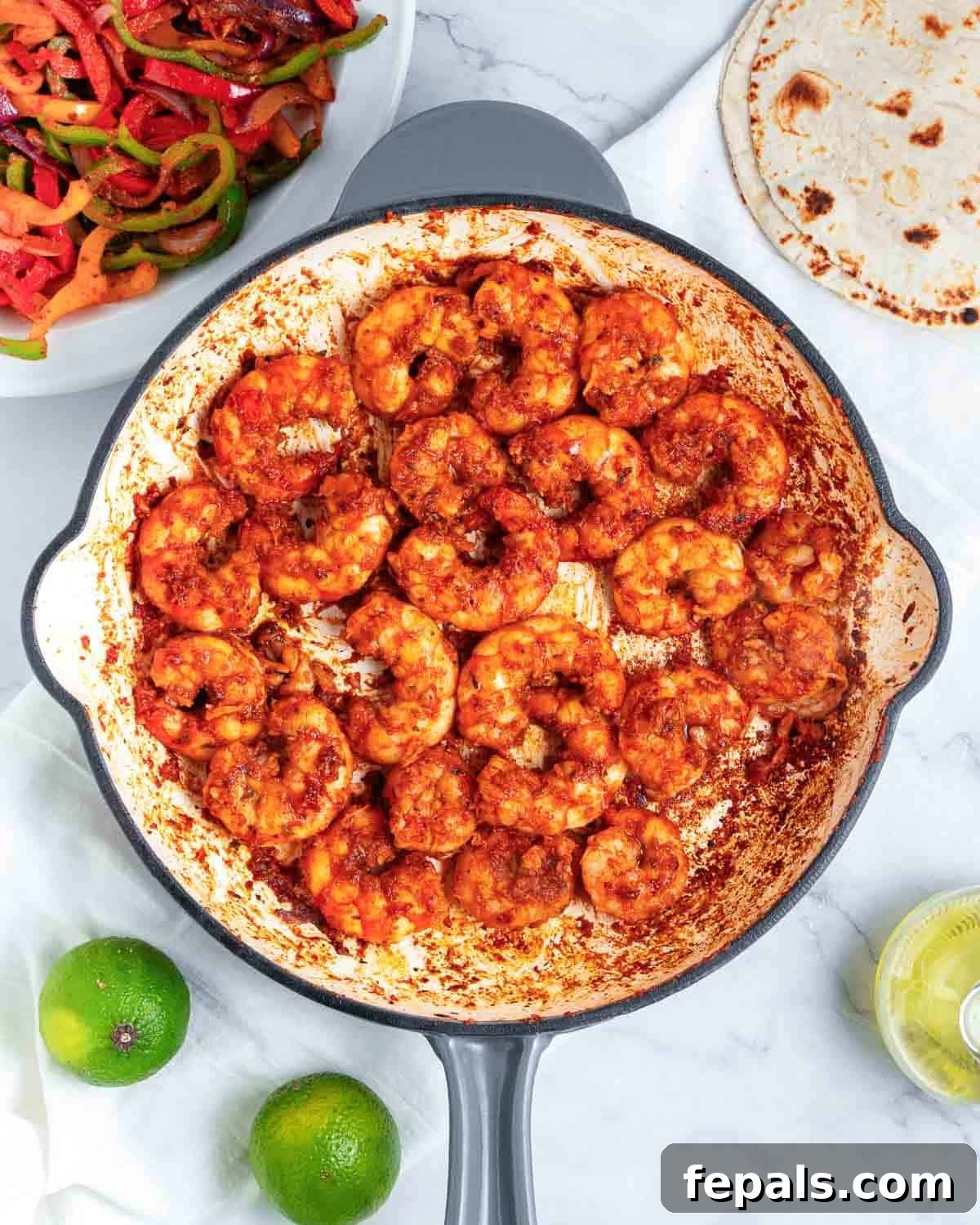 Perfectly cooked, pink, and curled shrimp in the skillet, ready to be combined with the seasoned vegetables.