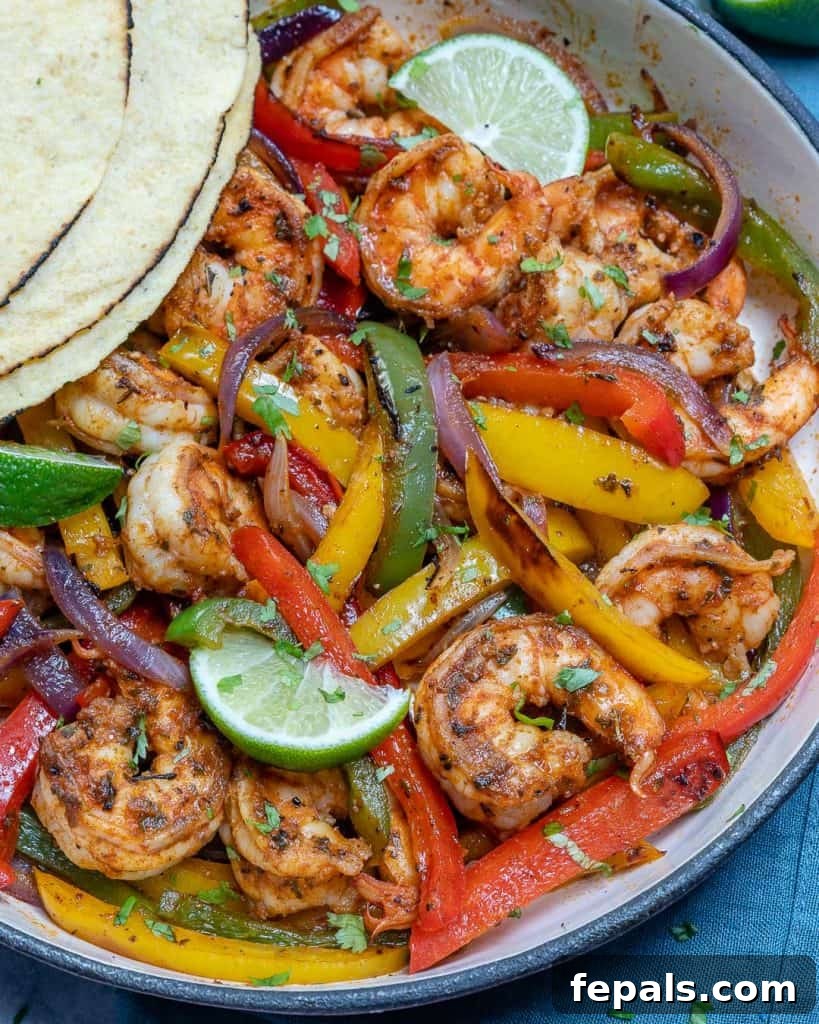 Top-down view of a cast-iron skillet filled with perfectly cooked shrimp fajitas, garnished with cilantro, showcasing the vibrant colors of the ingredients.