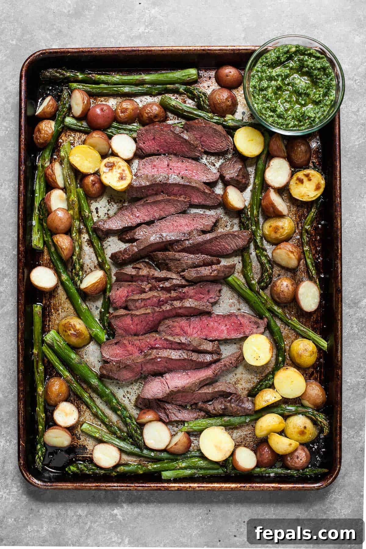 Sheet Pan Steakhouse Dinner 2 Sheet Pan Steak with Kale Pesto on baking sheet with potatoes and asparagus, ready to be served.